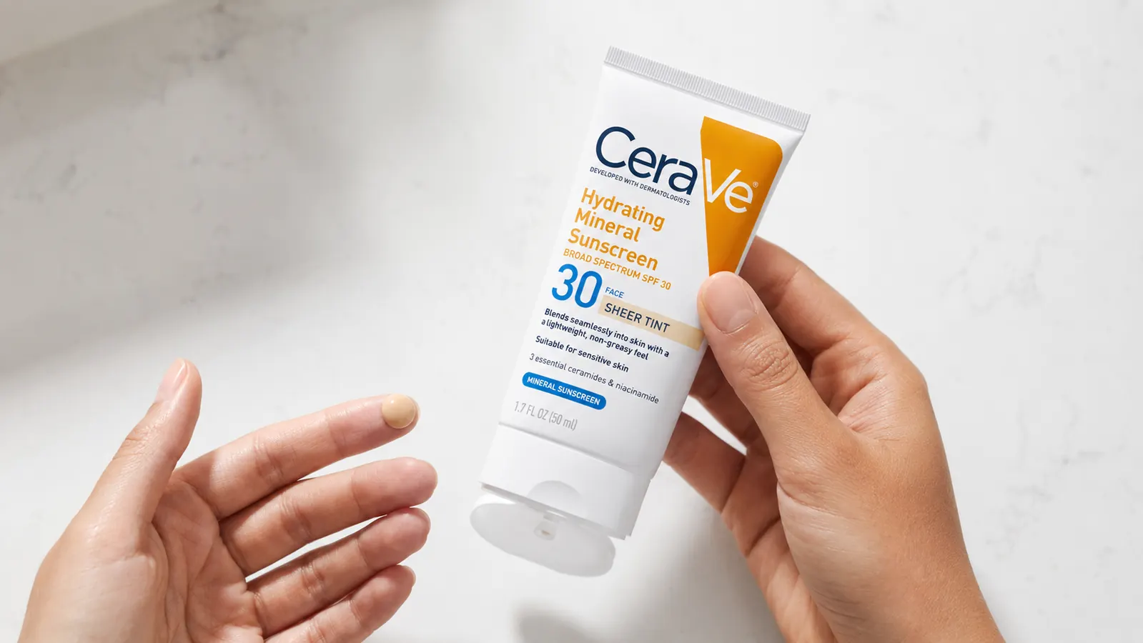 CeraVe Tinted Mineral Sunscreen tube held in hand showing product texture on fingertip