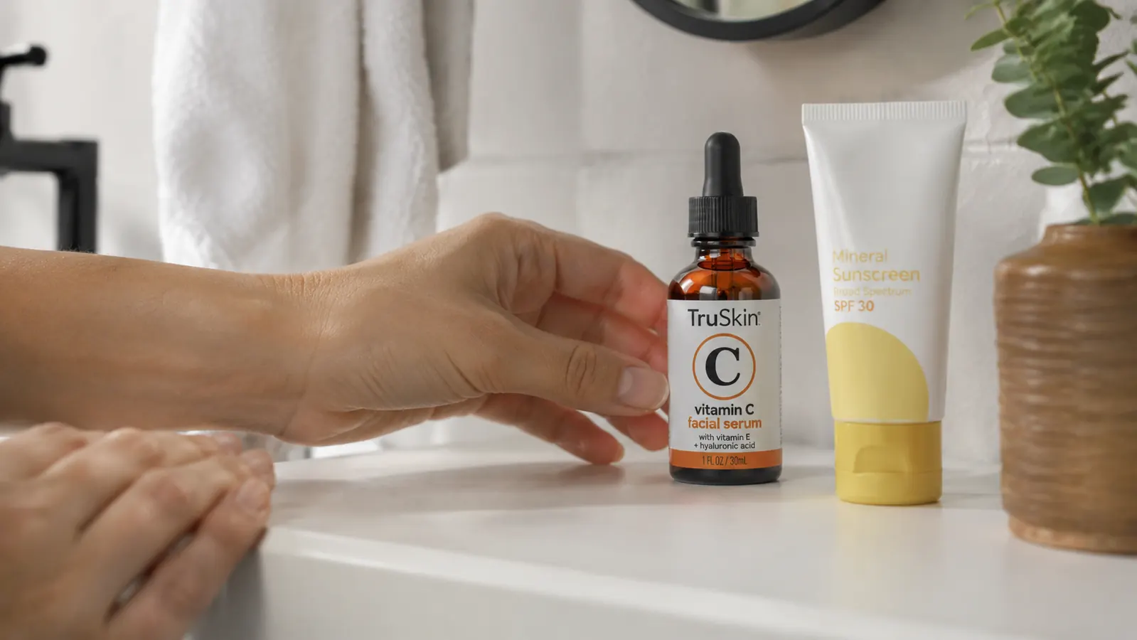 TruSkin Vitamin C Serum bottle next to sunscreen tube on a clean white bathroom shelf